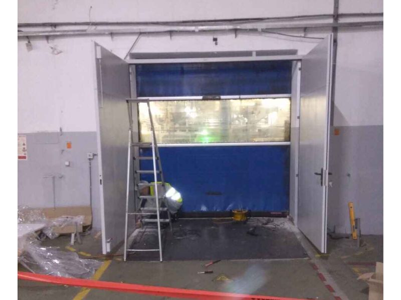 Н фоні білої стіни складського приміщення встановено протипожежні ворота, що є відкритими.