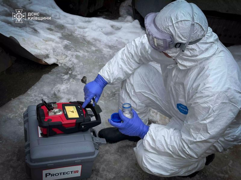 Сотрудник ГСЧС в защитном снаряжении использует портативный химический анализатор ProtectIR для идентификации вещества на открытой местности.