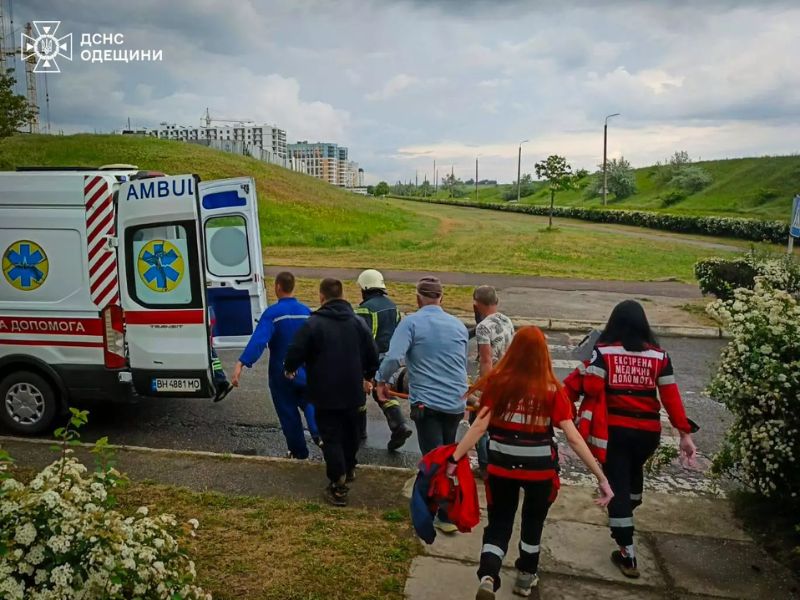 Рятувальники ДСНС та бригада екстреної медичної допомоги транспортують постраждалого на ношах до автомобіля швидкої допомоги.