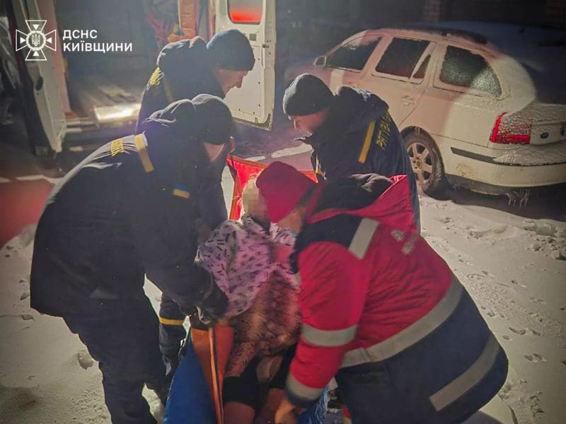 Пожарные ГСЧС Волынской области вытаскивают застрявшую в снегу машину скорой помощи с помощью троса днем.