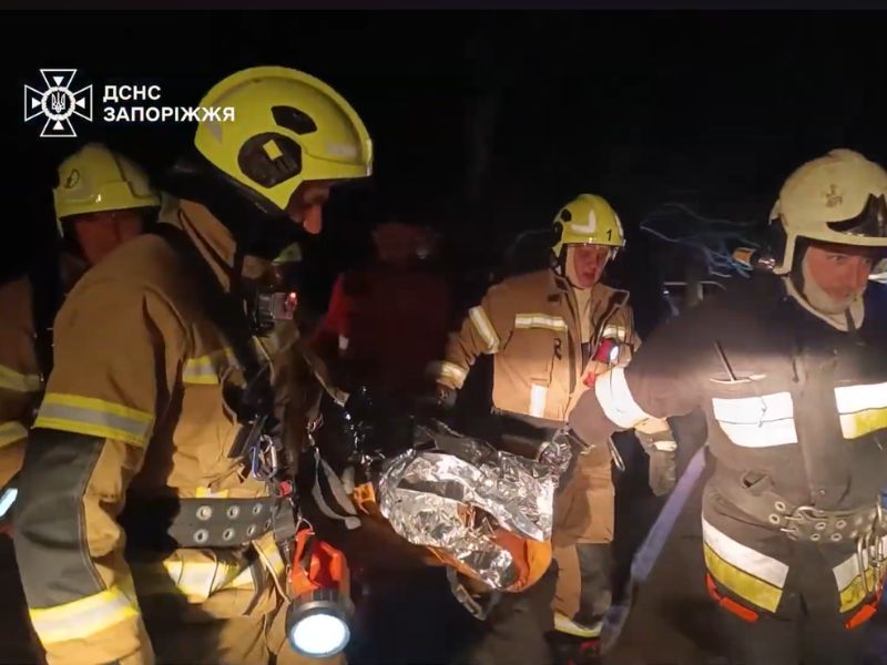 Рятувальники ДСНС виносять постраждалих із задимленого будинку в Запоріжжі для передачі медикам.