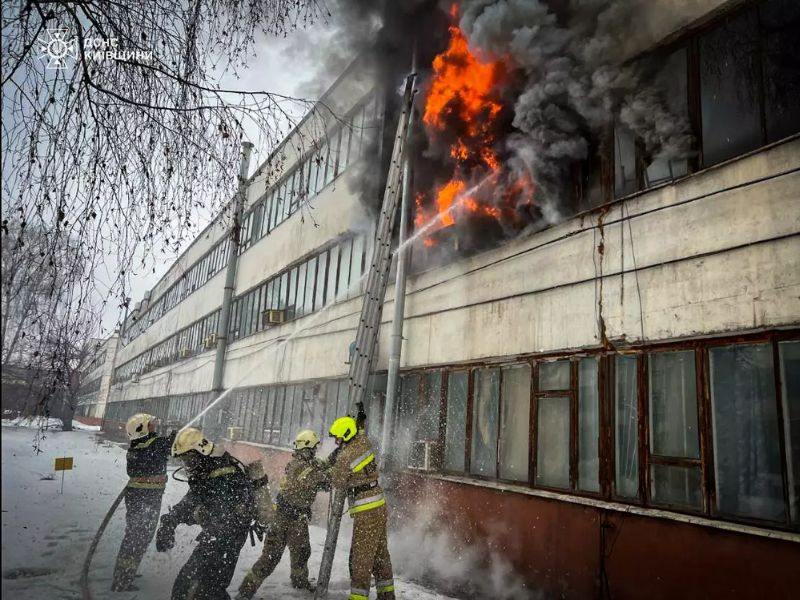 Рятувальники ДСНС ліквідовують пожежу в адміністративній будівлі на Київщині. Вогнеборці за допомогою пожежної драбини подають воду на гасіння відкритого вогню на верхніх поверхах серед снігу та диму.