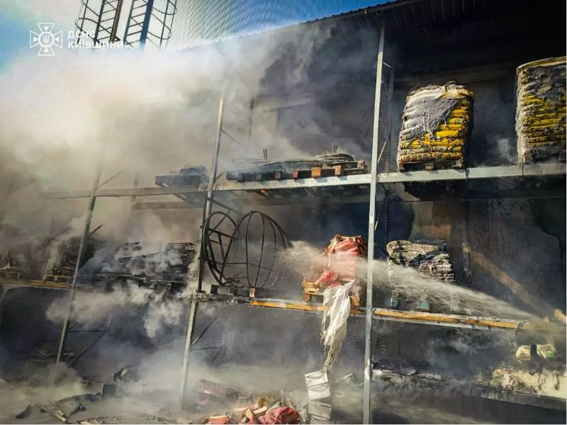 Пожарные ГСЧС ликвидируют возгорание на складе в Киевской области: струя воды направлена на горящие стеллажи с товаром среди густого дыма.