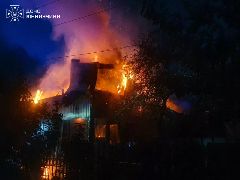 Бійці ДСНС працюють біля палаючої покрівлі будівлі у Вінниці, аби не допустити поширення полум'я на розташовані поруч споруди.