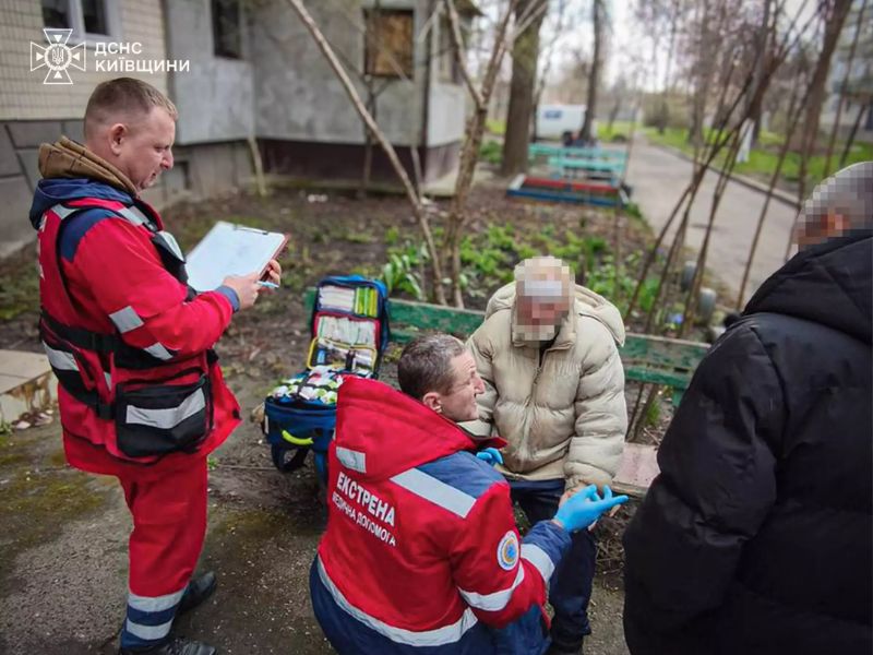 Сотрудники службы Екстрена медична допомога оказывают помощь пострадавшему после пожара в Киевской области.