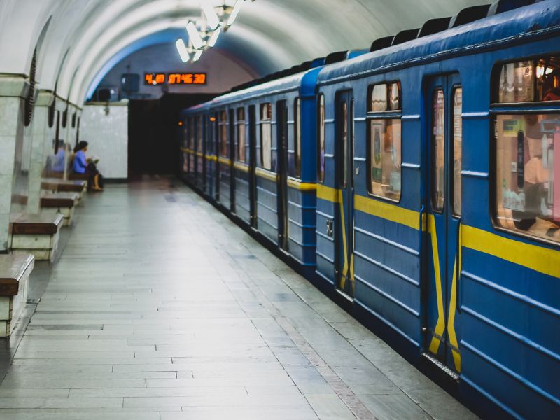 Станція метро вокзальна київського метрополітену, на лавці сидить жінка, вагон метро під'їхав і стоїть на станції. Ваго виконаний у жовто-блакитних кольорах.