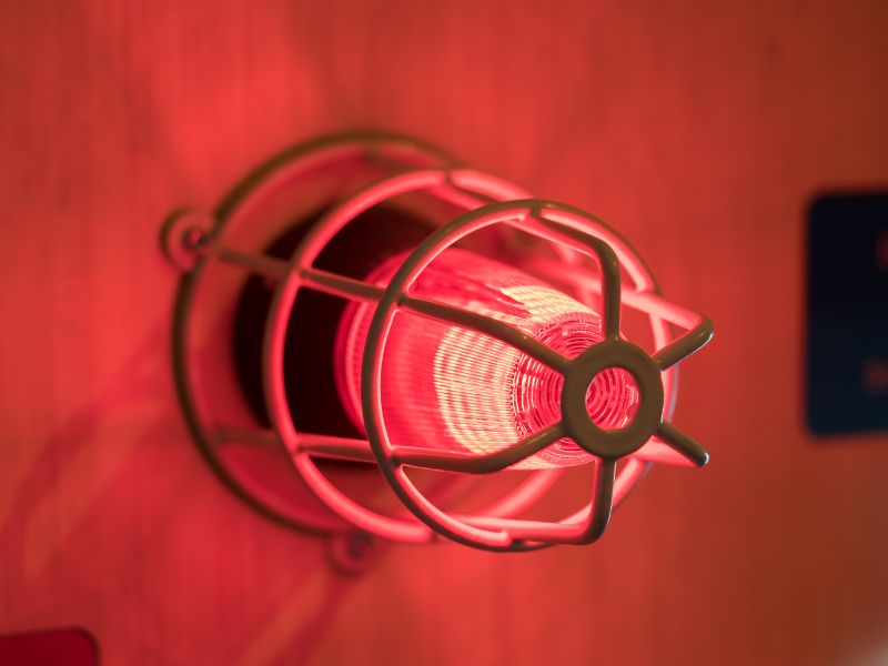 На стіні причеплена лампа червоного кольору яка подає червоне світло сигналізуючи про тривогу, а саме пожежу