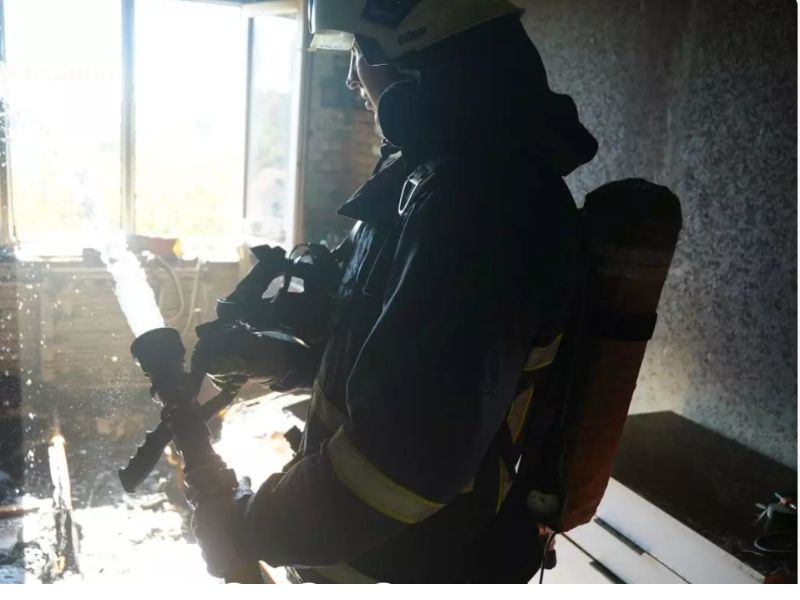 Рятувальник ДСНС у дихальному апараті ліквідує загоряння в житловій кімнаті за допомогою пожежного ствола у Житомирі.