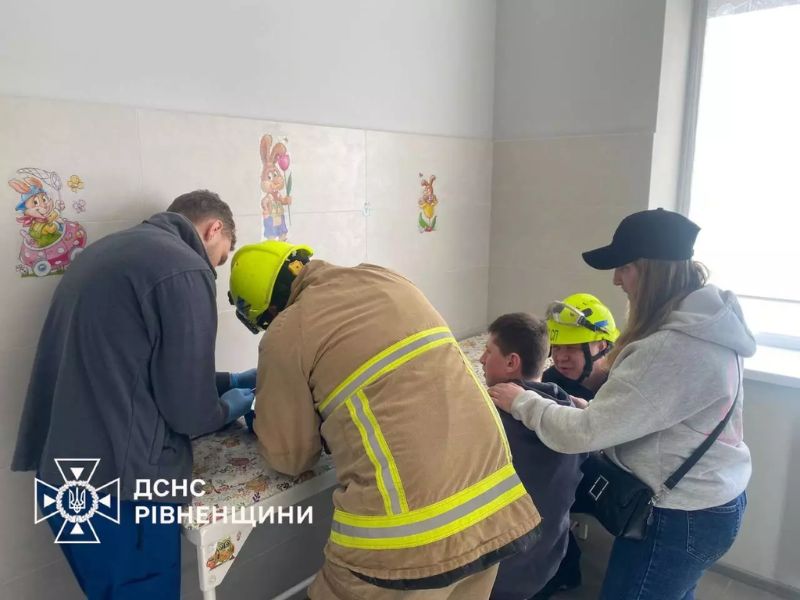 Сотрудники ДСНС в защитном снаряжении и шлемах помогают подростку снять застрявшее кольцо в больнице Ровенской области.