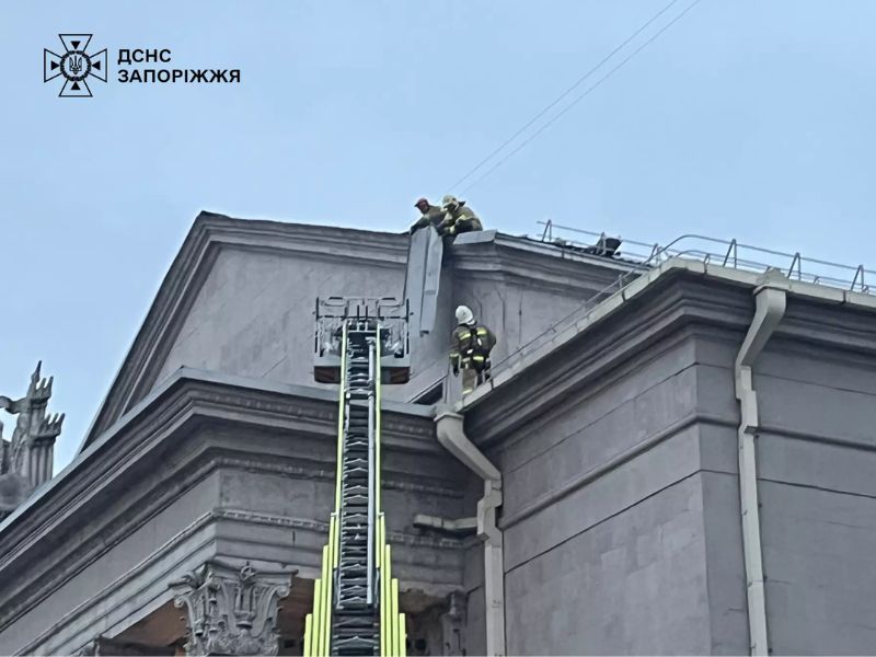 ятувальник ДСНС на даху будівлі поруч із люлькою пожежної автодрабини під час виконання робіт.