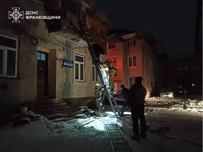 Рятувальники ДСНС Івано-Франківщини використовують висувну драбину для евакуації або доступу до приміщення будівлі УТОС під час нічної рятувальної операції взимку.