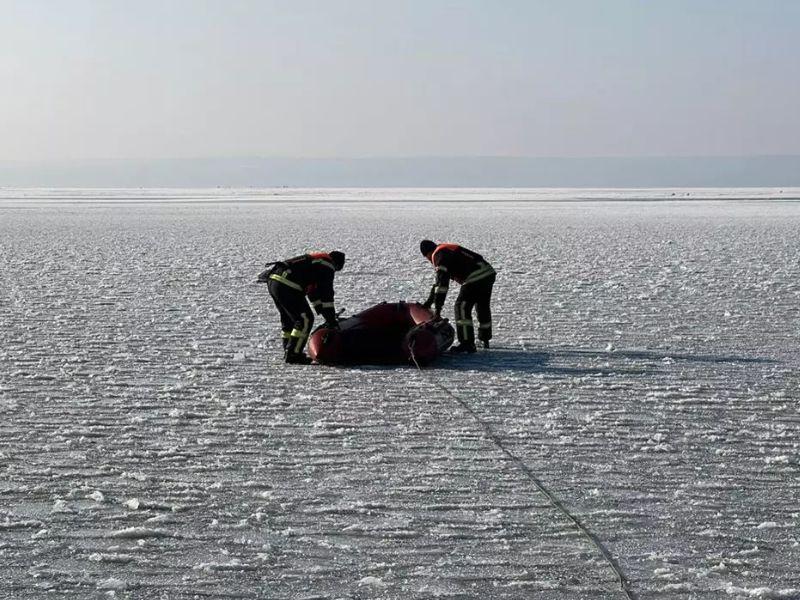 Рятувальники ДСНС на тонкій кризі використовують надувний човен та страхувальний канат для проведення рятувальної операції на замерзлій водоймі.