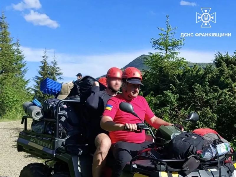 Співробітник ДСНС на квадроциклі транспортує туриста та його похідне спорядження гірською дорогою у безпечне місце.